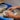 A person sat at a potting wheel pulling a pot.